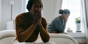 unhappy black couple sitting on bed after having argument