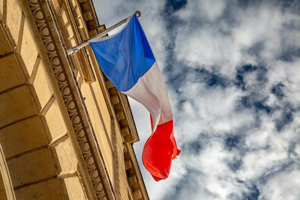 french flag flying against a cloudy sky in paris